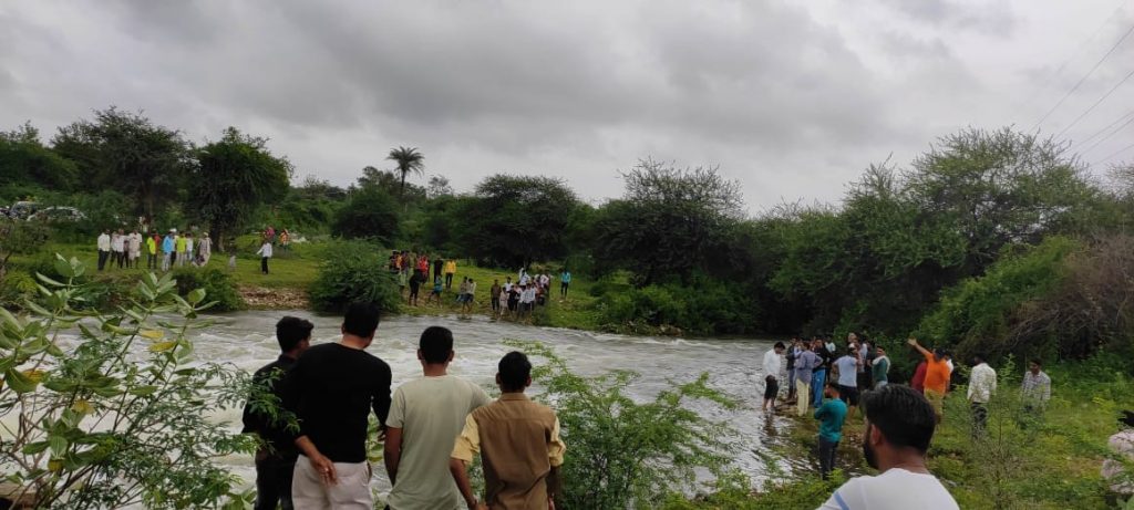कादंबरी बांध के ओवरफ्लो होने से रपट पर बह रहे पानी में एक मोटरसाइकिल बहने की खबर ।